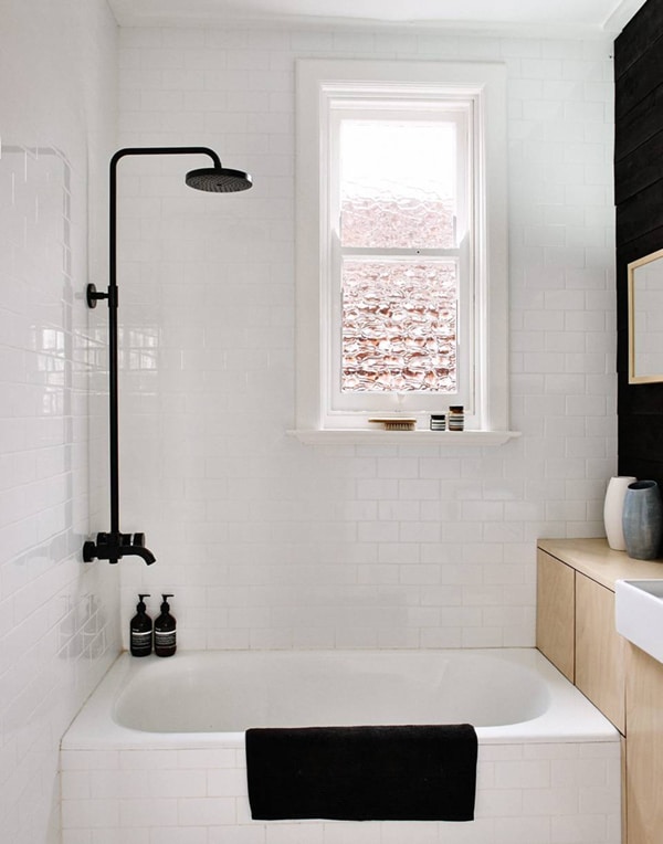 small bath with white subway tiles and black fixtures and touch of wood