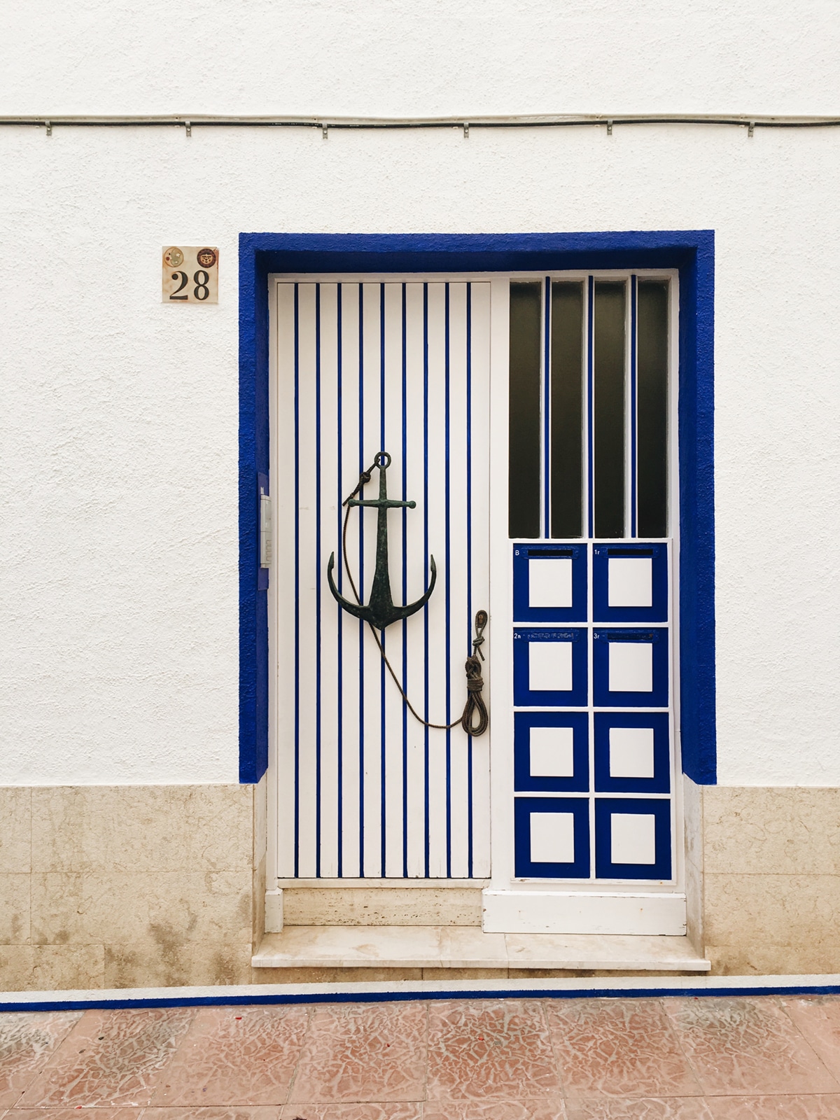 a charming blue and white door with anchor in sitges | spain travel guide on coco kelley