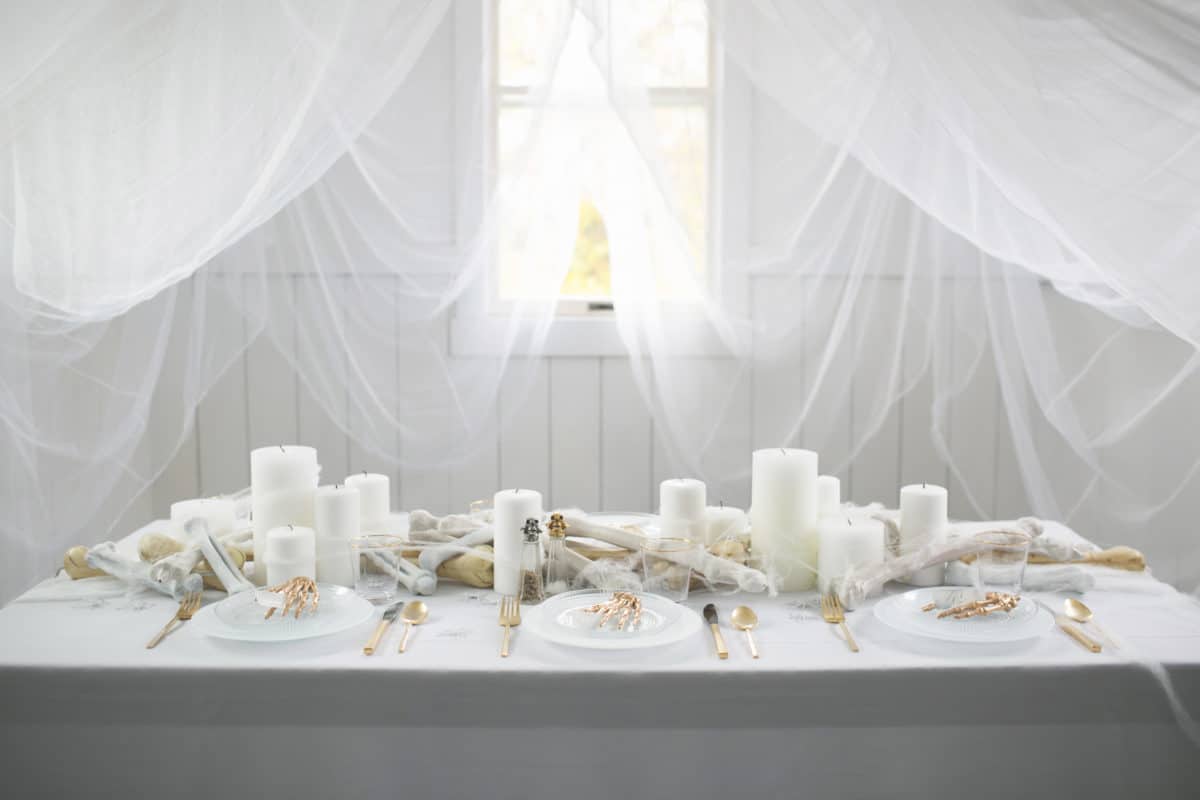 an all white ghostly halloween tabletop with bone and candle centerpiece runner | coco kelley