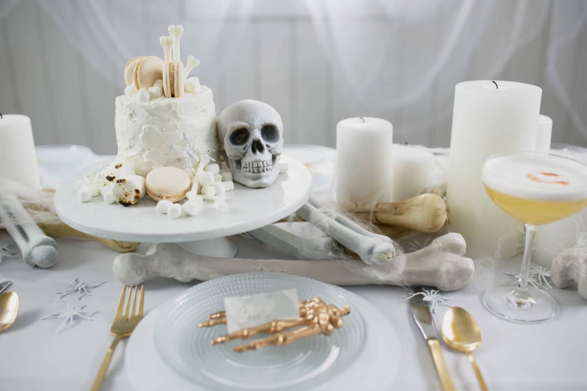 an all white ghostly halloween tabletop with skull and bone cake | coco kelley-11