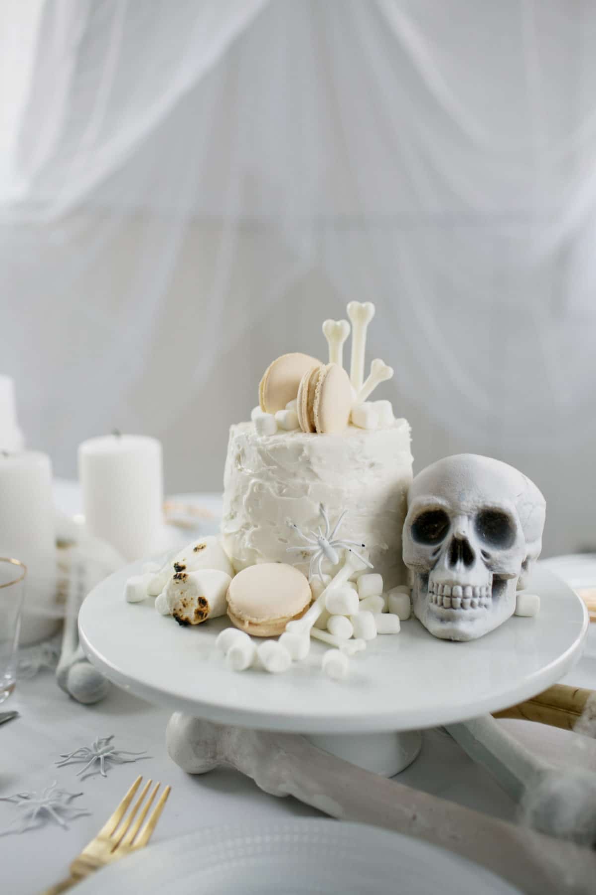 an all white ghostly halloween tabletop with skull and bone cake | coco kelley