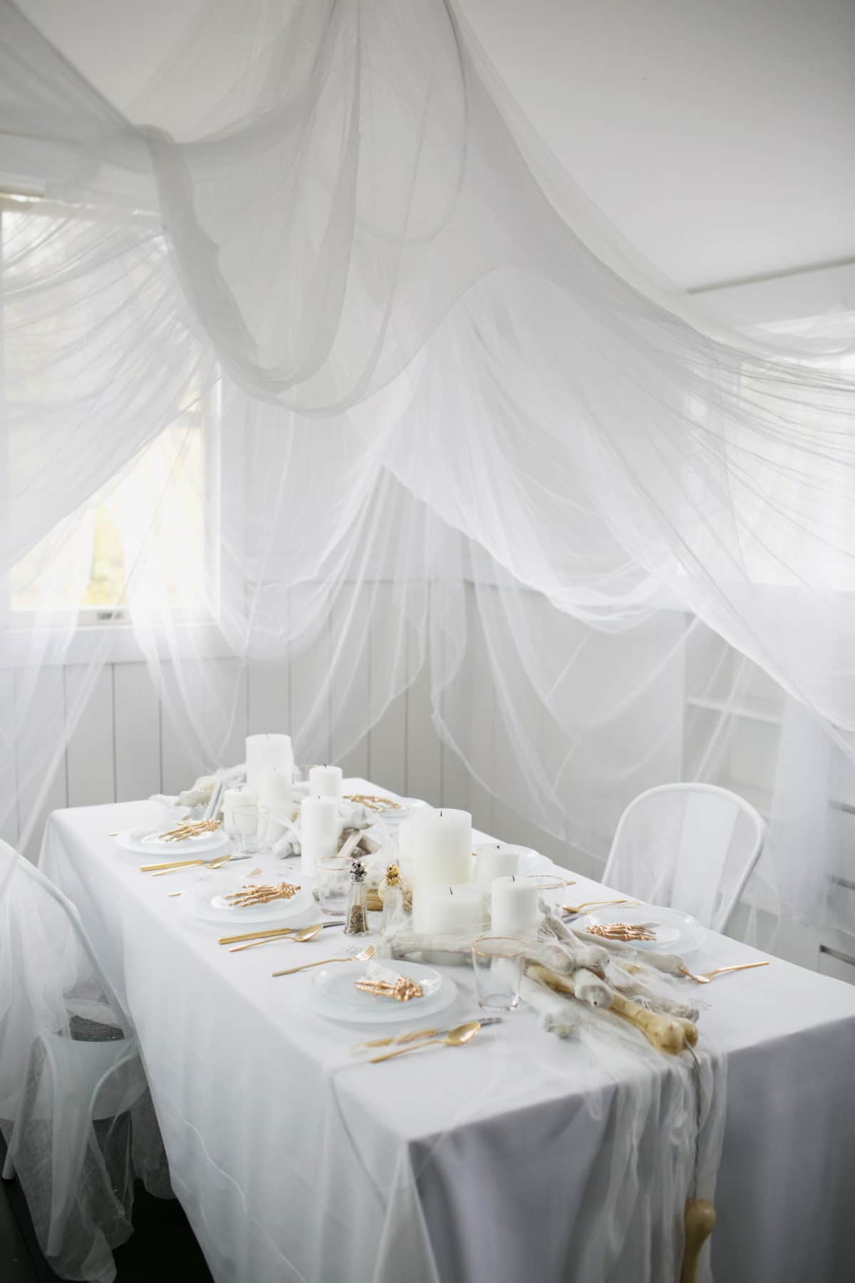 an all white ghostly halloween tabletop with bone and candle centerpiece runner | coco kelley