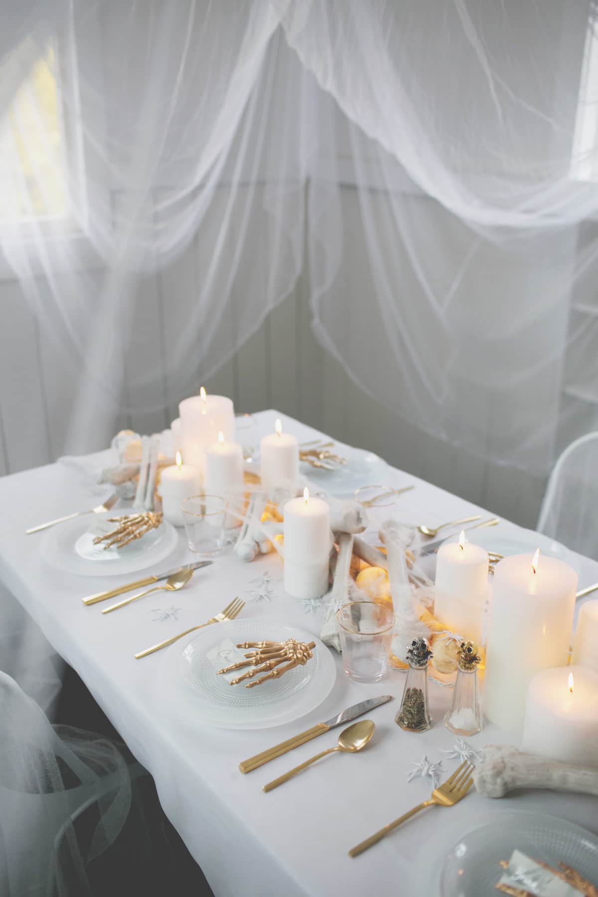 an all white ghostly halloween tabletop with bone and candle centerpiece runner | coco kelley