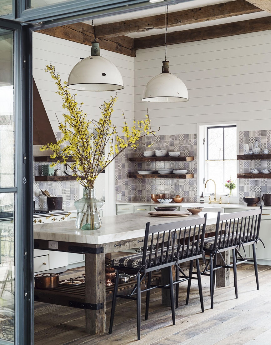 an eclectic farmhouse kitchen boasts tiled walls, industrial pendants, and counter bench seats | home tour on coco kelley