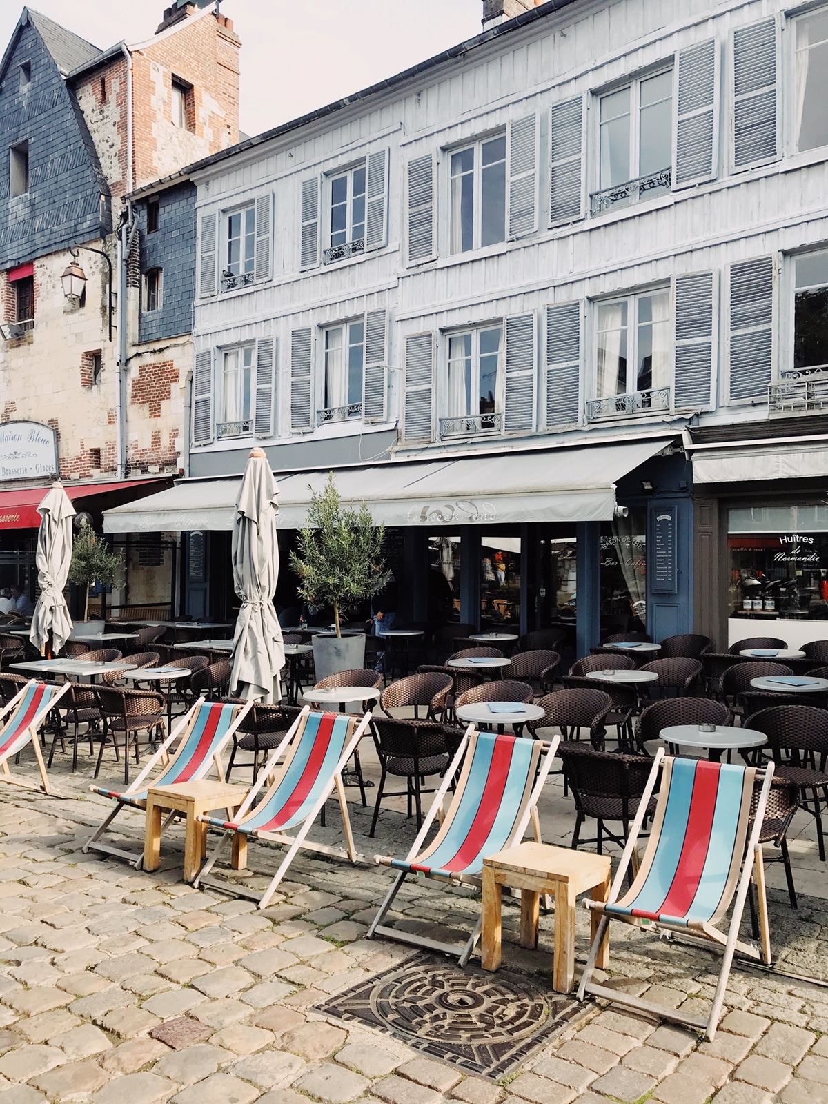 beach loungers in front of a weather worn restaurant in Honfleur | normandy france travel guide 