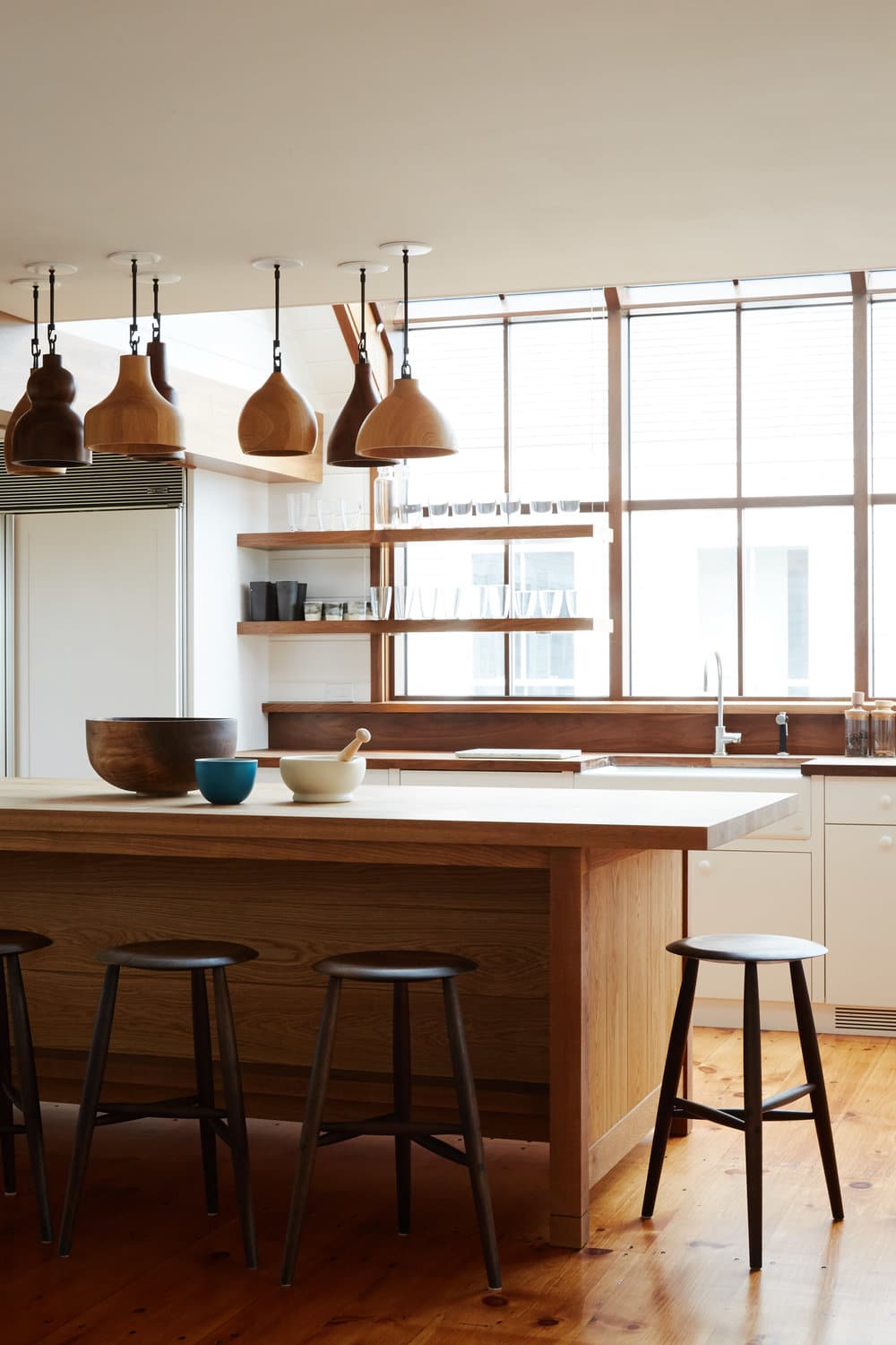 collected wood pendants over a wood island in the kitchen | modern shaker beach house tour on coco kelley