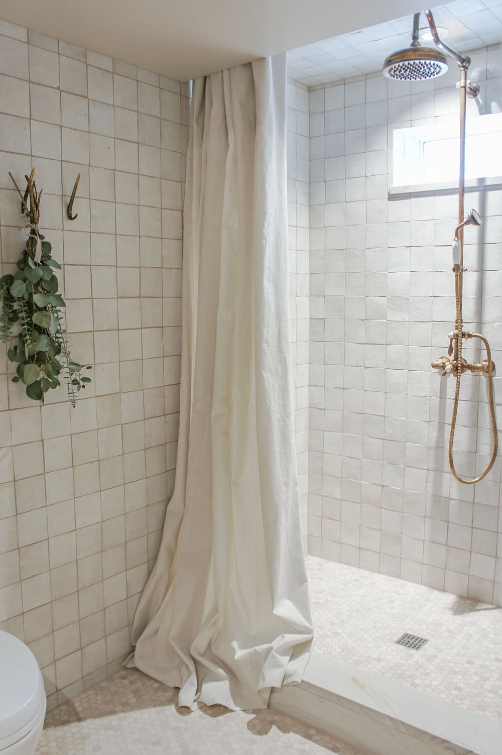 cream zellige tiles and brass hardware in the shower
