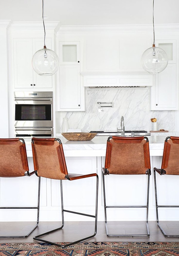 an all white kitchen gets a hit of industrial style from these bar stools | via coco kelley
