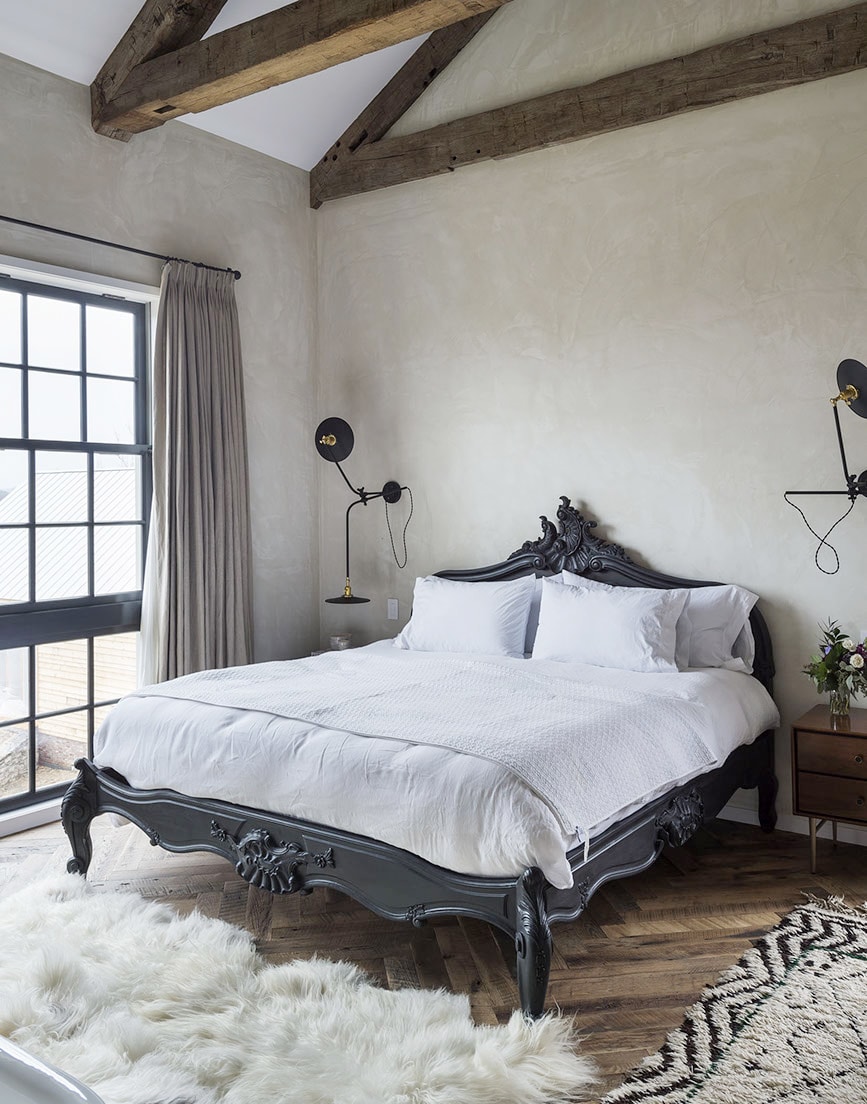 master bedroom with modern sconces, european bed, white linens and cozy rugs | full farmhouse tour on coco kelley