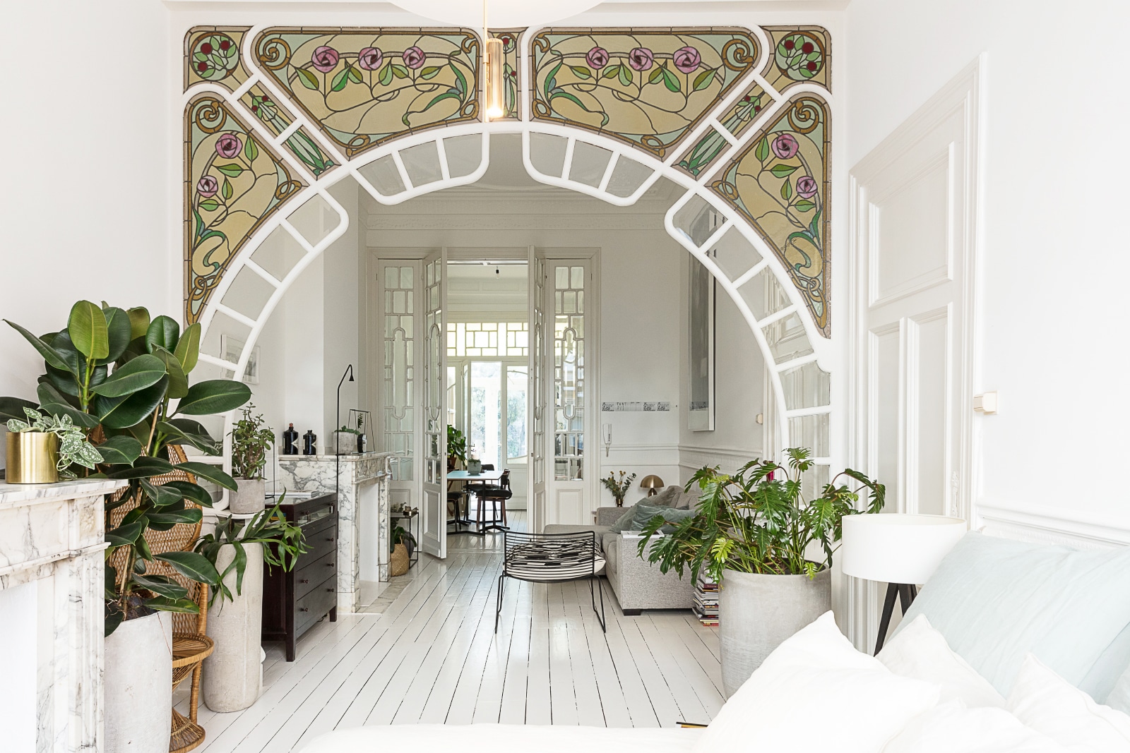 nouveau bohemian apartment in white with stunning stained glass window archways | house tour on coco kelley