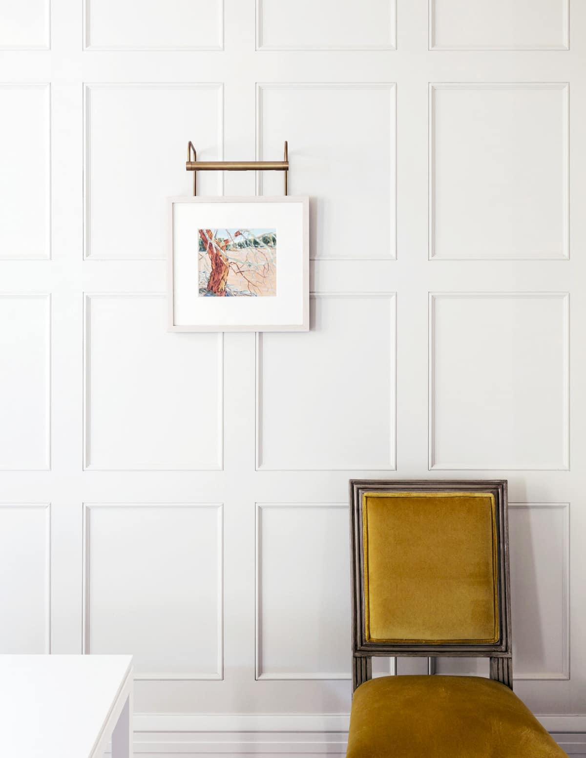 ochre yellow velvet dining chair and art on a paneled wall | house tour on coco kelley