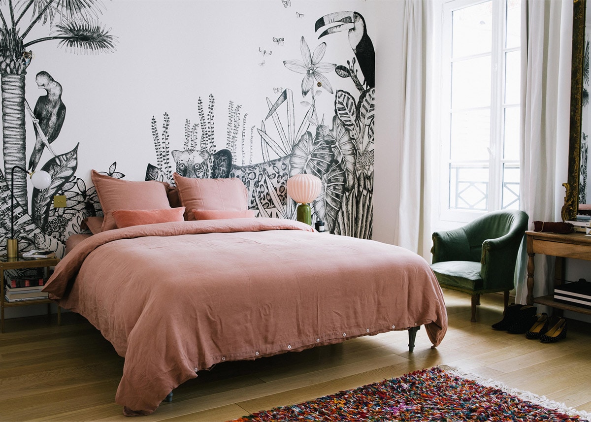 pink linen sheets and a black and white jungle mural in the bedroom | a happy chic parisian apartment tour via coco kelley