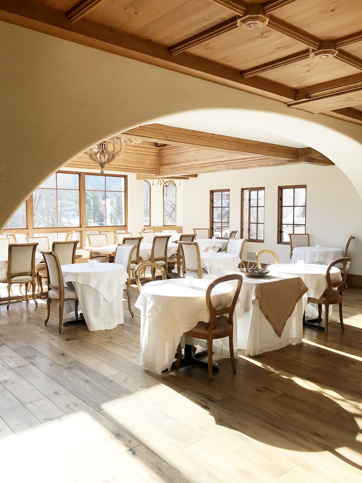 the dining room at the posthotel in leavenworth warm woods and white linens | coco kelley