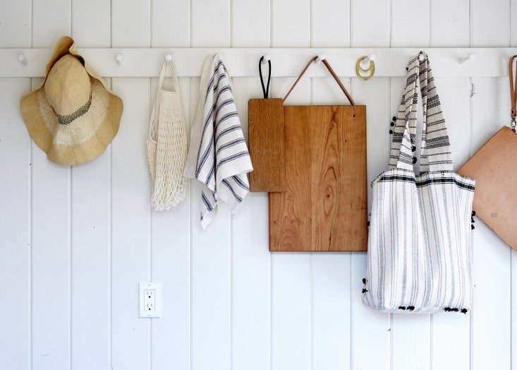 the kitchen entryway pegs hold everything from hats to cutting boards | via coco kelley