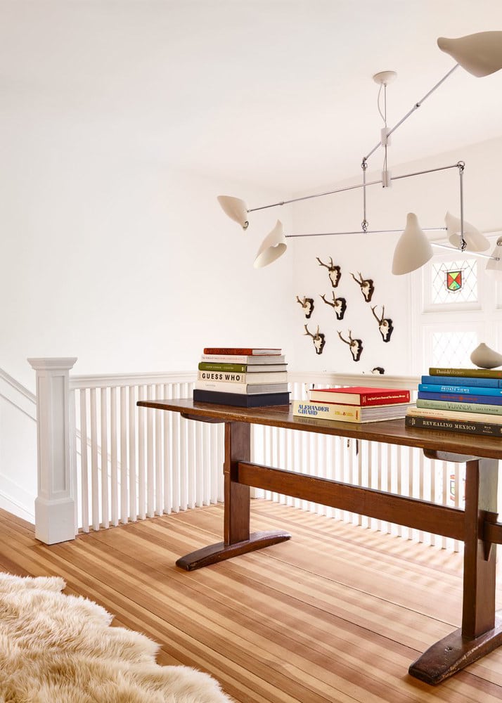 the-landing-is-filled-by-a-table-piled-with-books-house-tour-via-coco-kelley