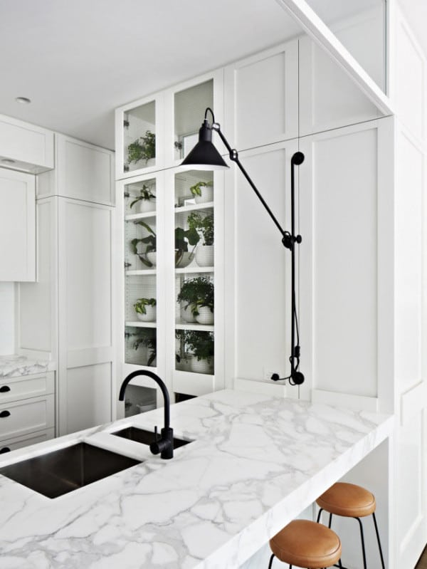 modern black and white kitchen with leather stools, marble counters, black fixtures