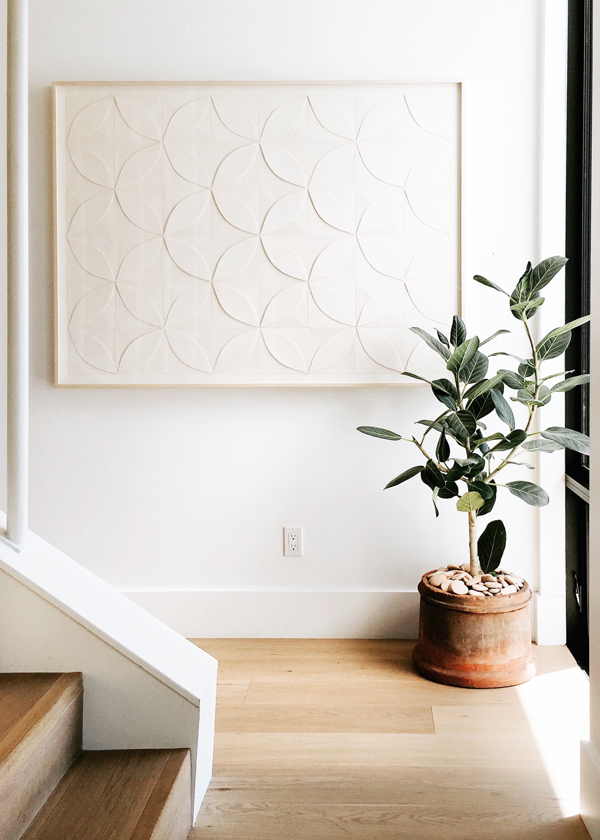 white artwork and rubber tree plant in terra cotta pot entryway landing | photo by cassandra lavalle